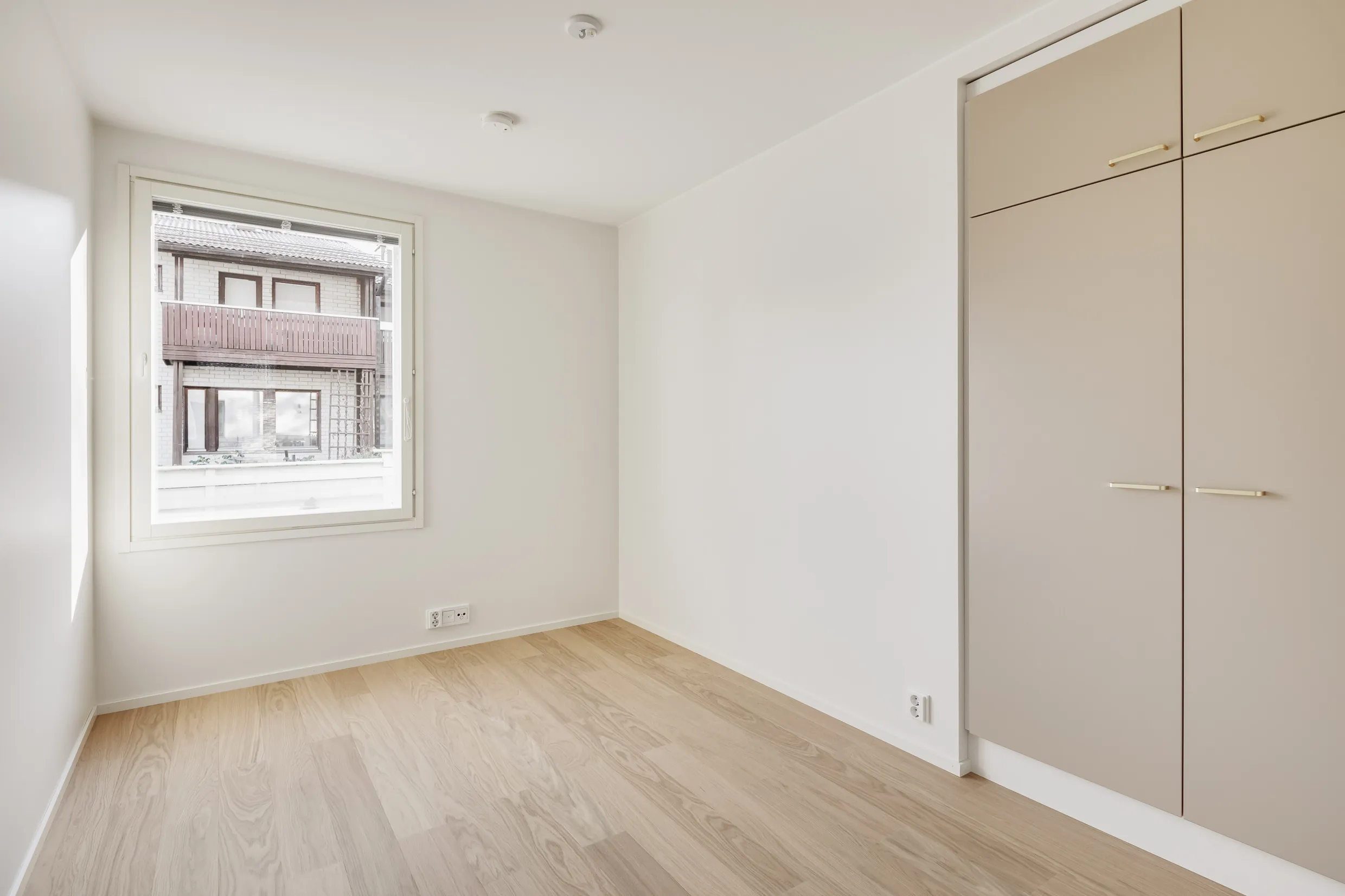 Vaalea huone, ikkuna ja vaatekaappi, puulattia.