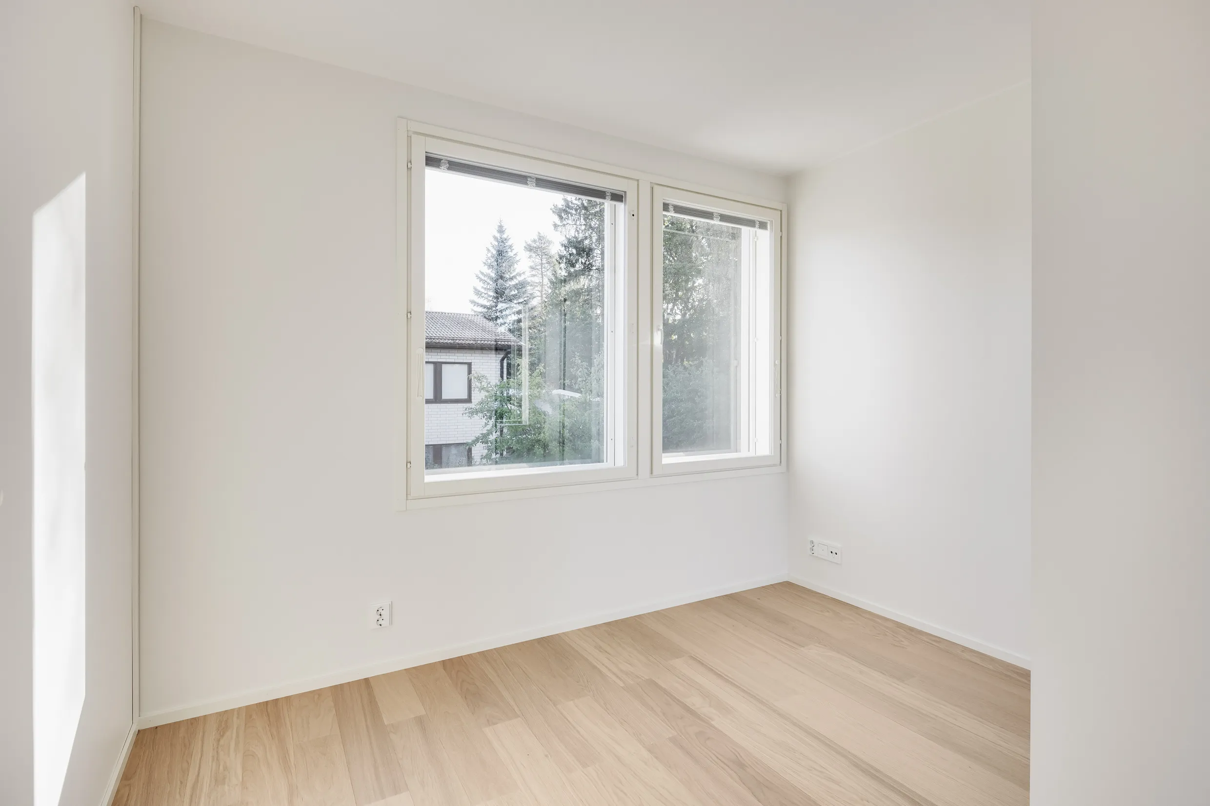 Vaalea huone, ikkunat, puulattia.