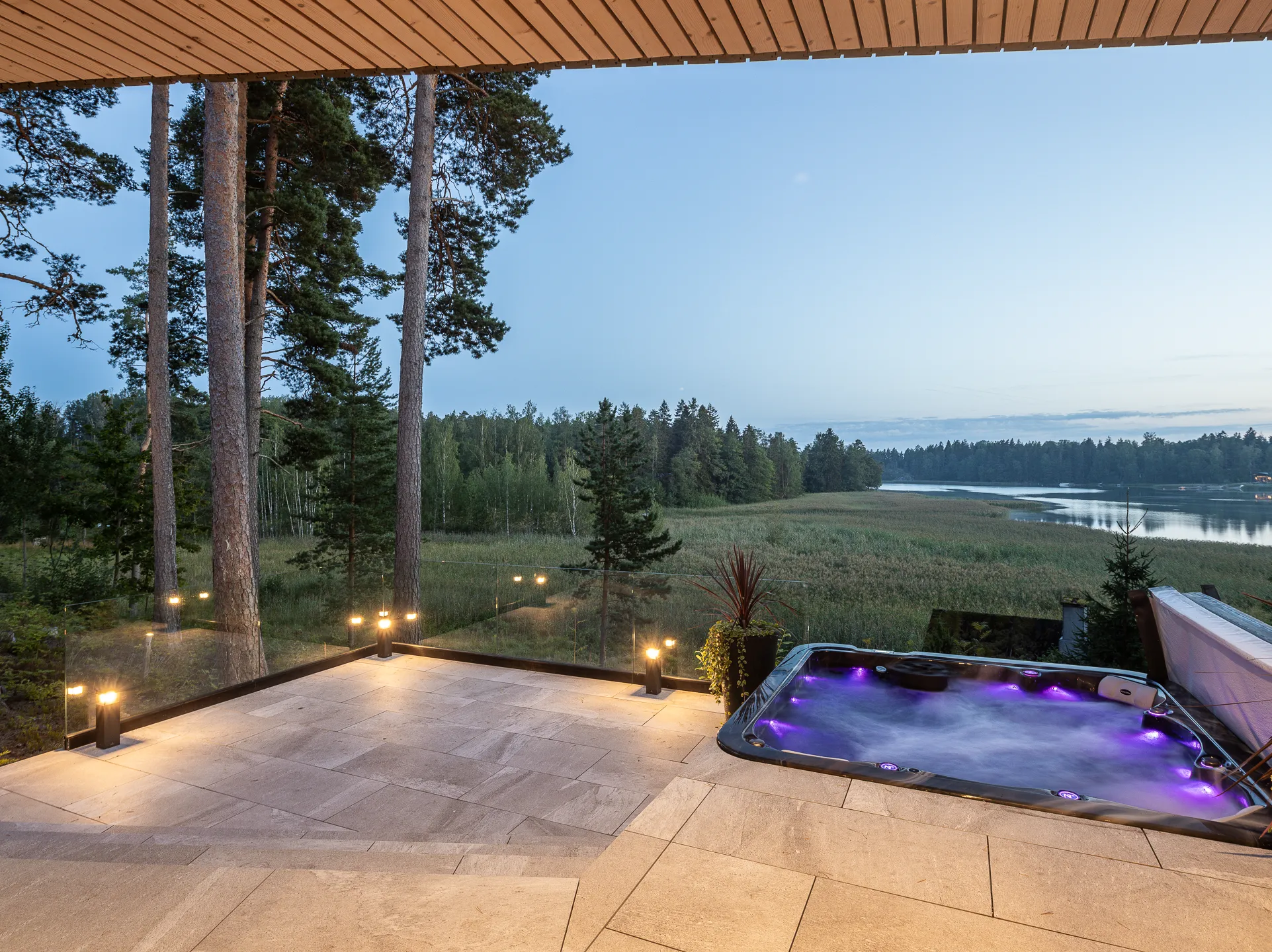 Ulkona sijaitseva poreallas terassilla, valaistus ja metsämaisema taustalla.