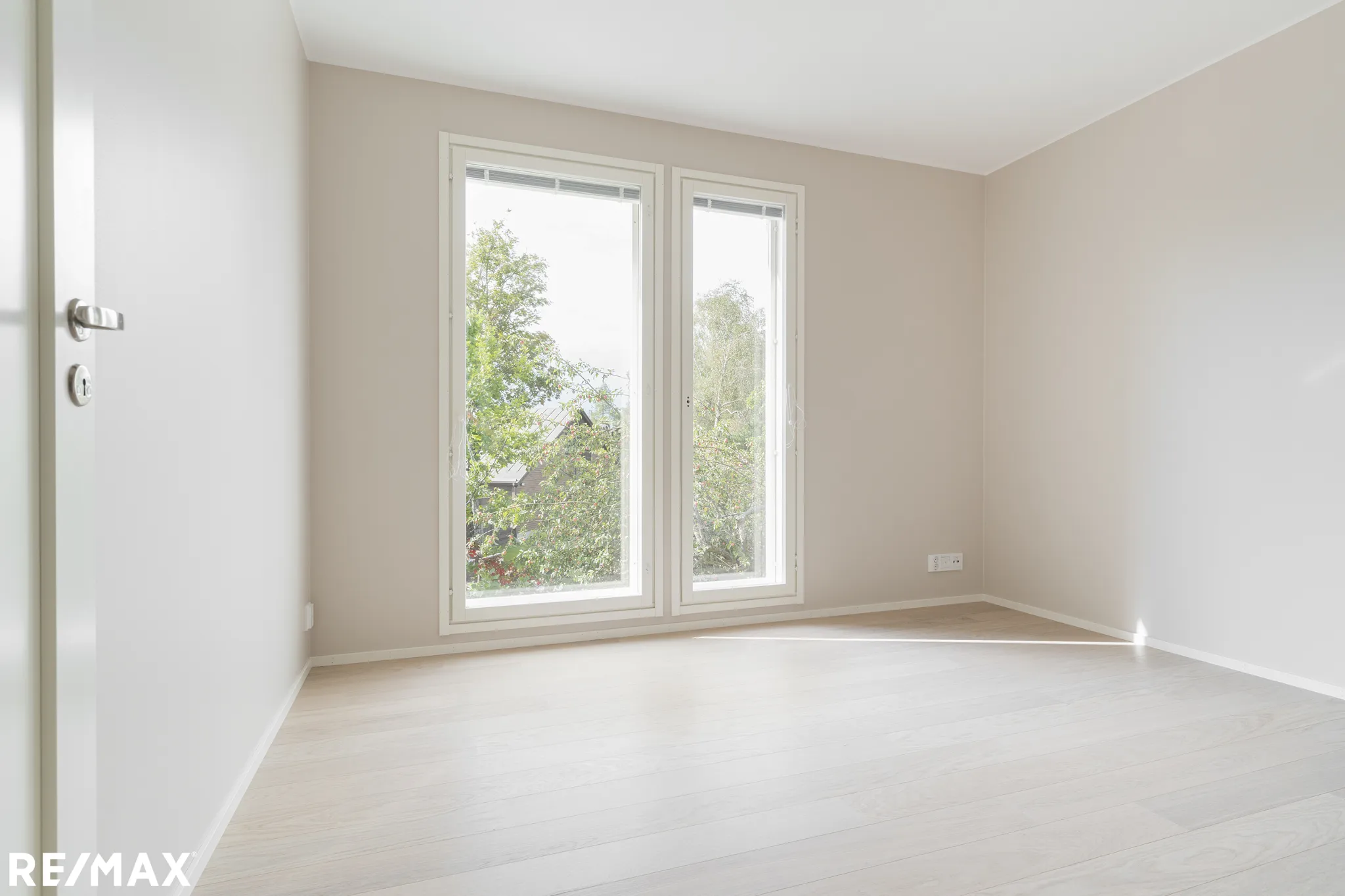 Vaalea huone, ikkunat ja RE/MAX-logo.