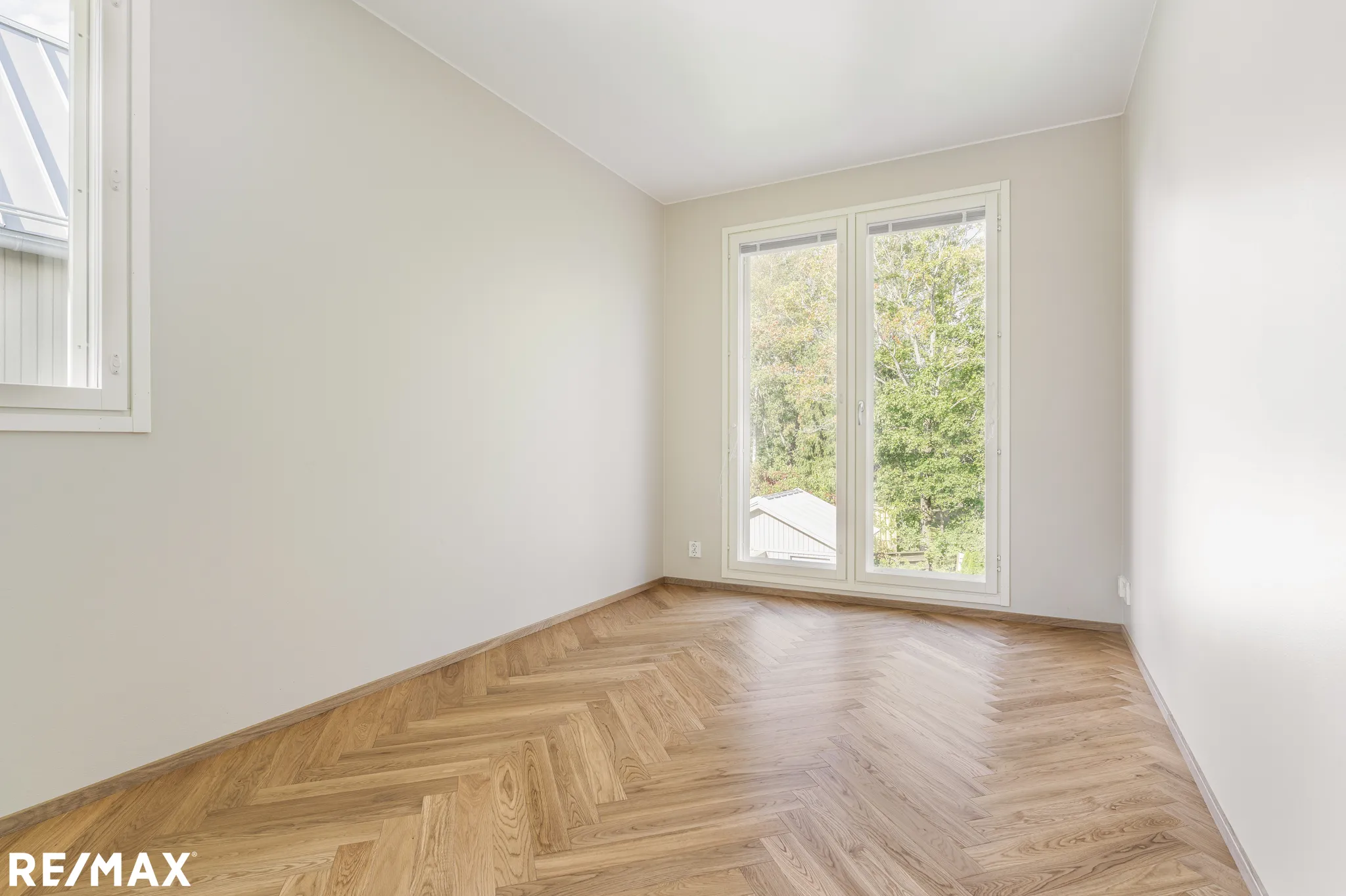 Vaalea huone, parkettilattia ja ikkunat.