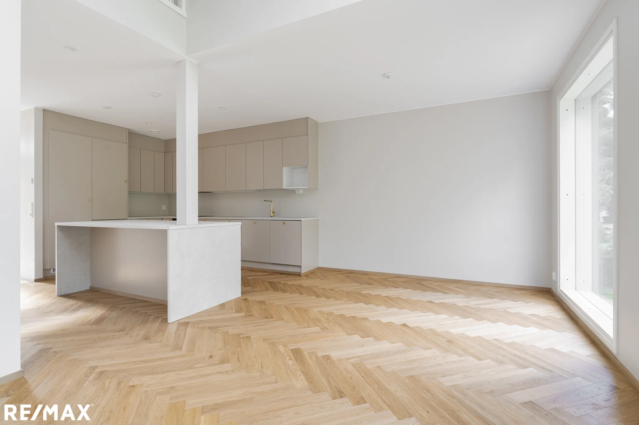 Vaaleassa huoneessa on vaaleat puulattiat, vaaleat keittiökaapit ja suuri ikkuna, joka päästää sisään luonnonvaloa.