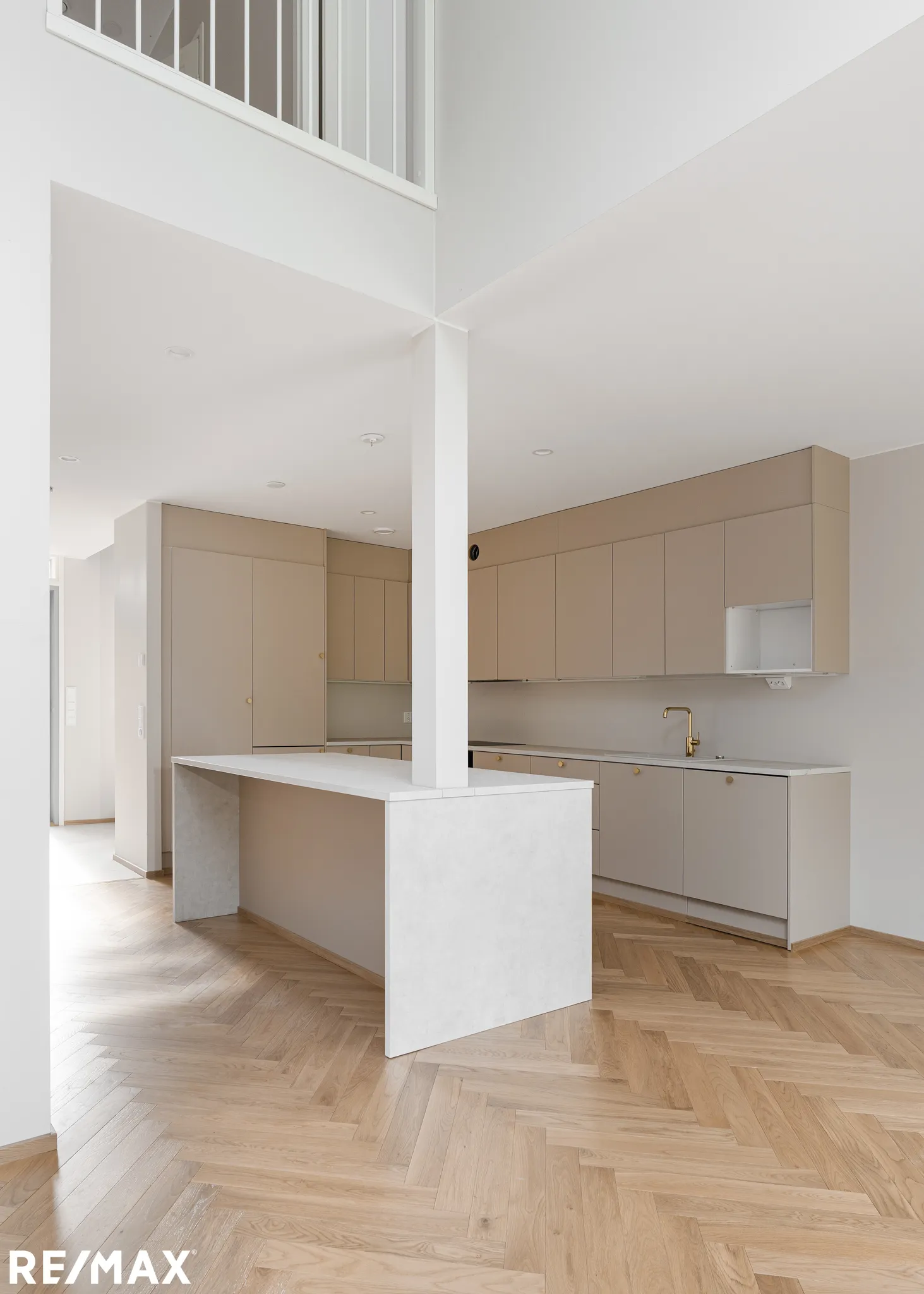 Vaalean keittiön sisustus, jossa on kalanruotokuvioinen parketti ja valkoinen keittiösaareke.