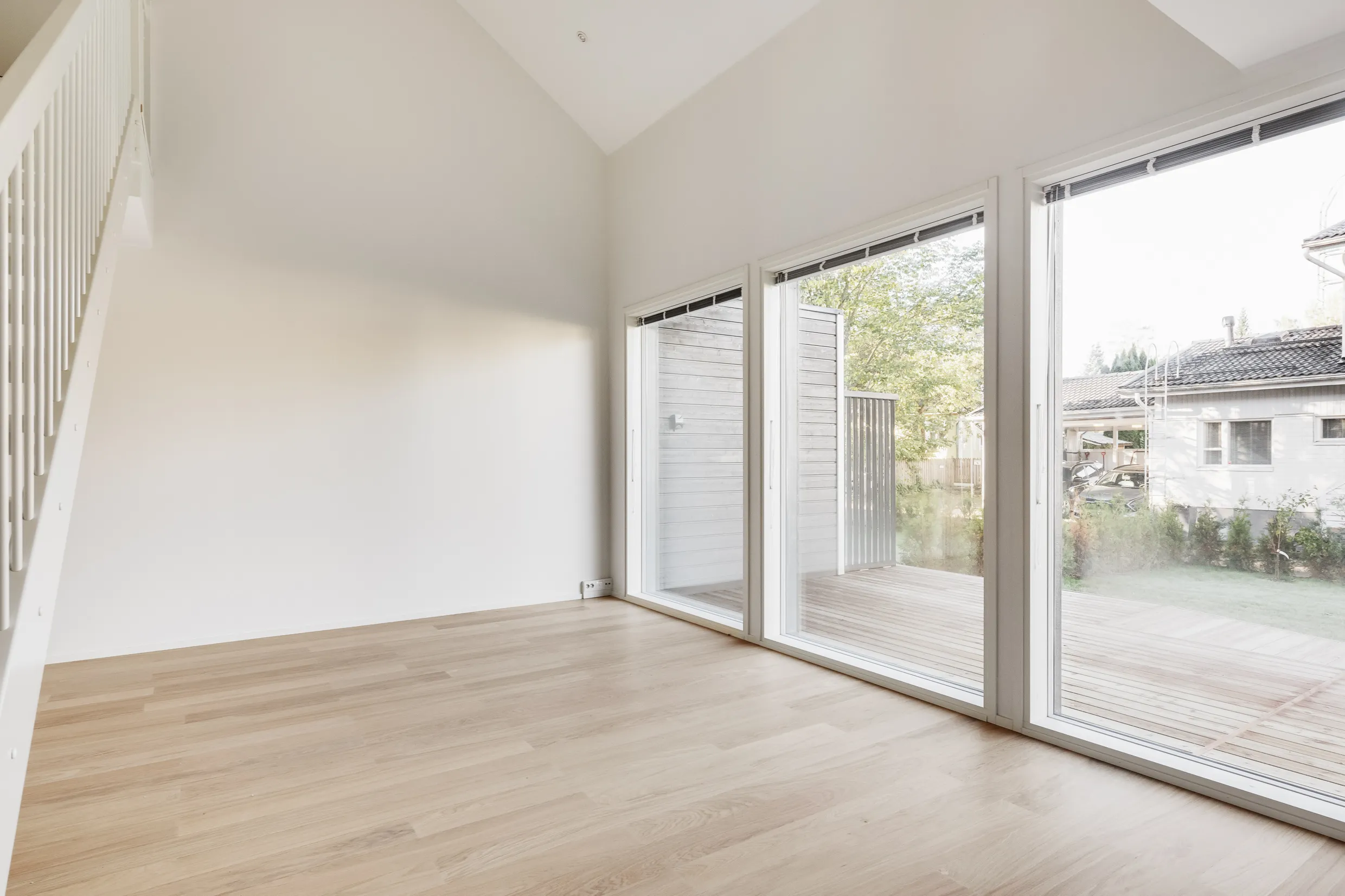 Vaalea huone, puulattia, suuret ikkunat.