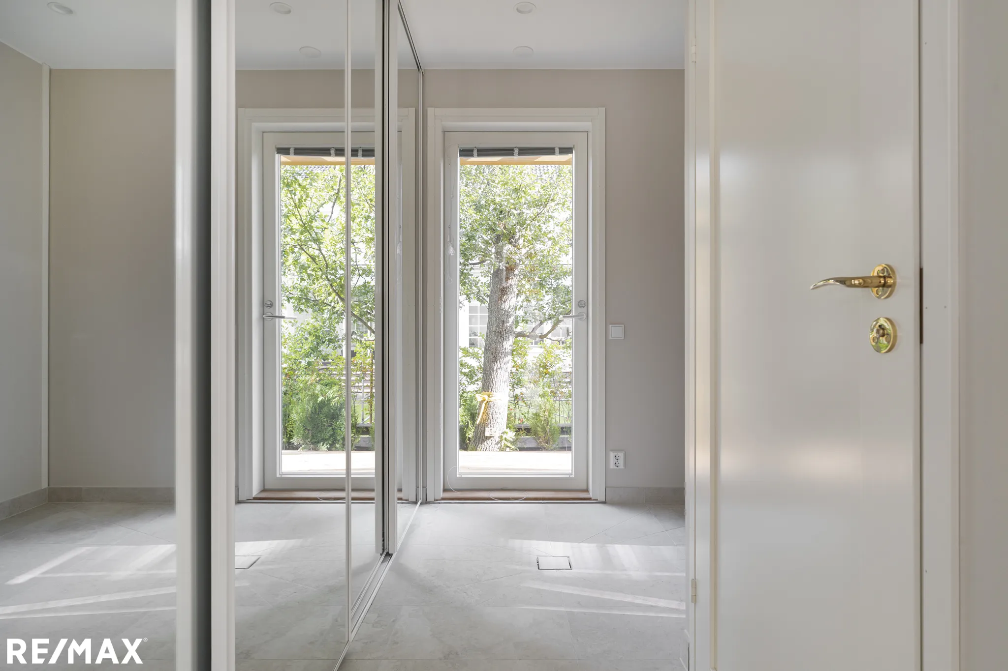 Vaalea huone, peilikaappi, ulko-ovi, valoisa.