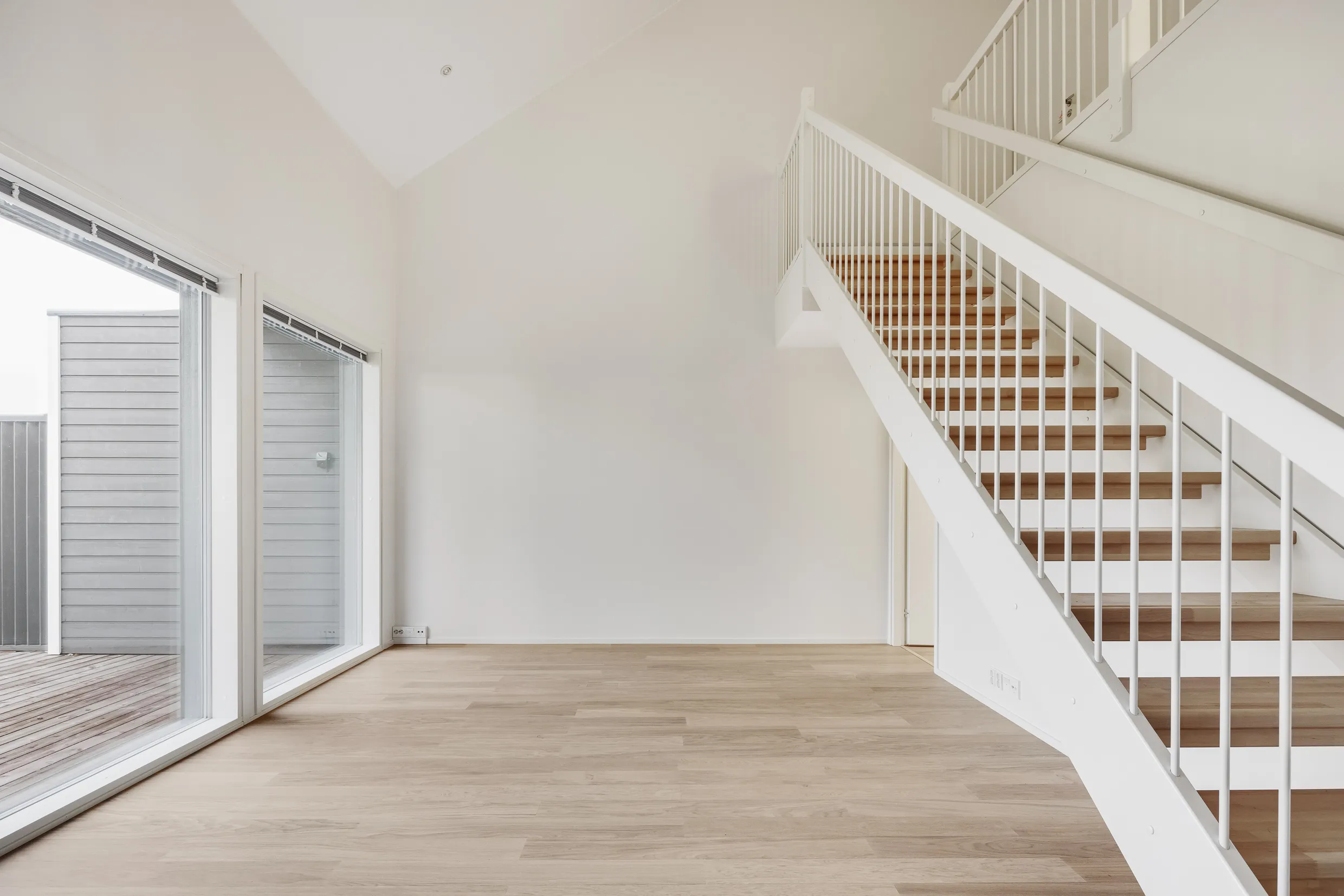 Vaalea huone, portaat, ikkunat.