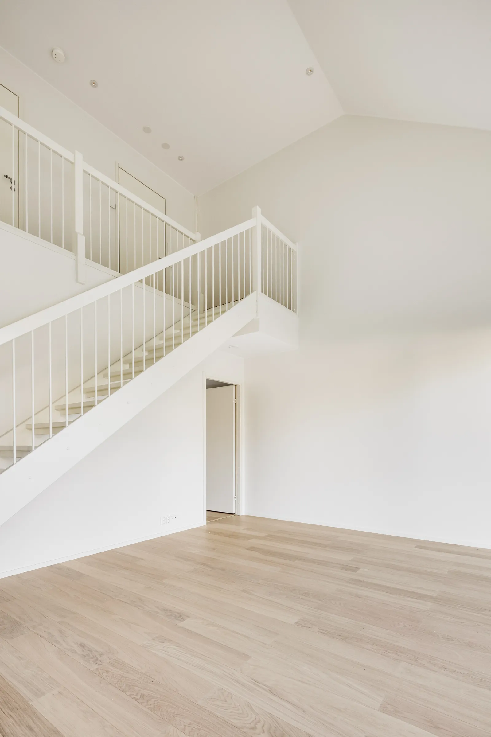 Vaalea huoneisto, portaat ja puulattia.