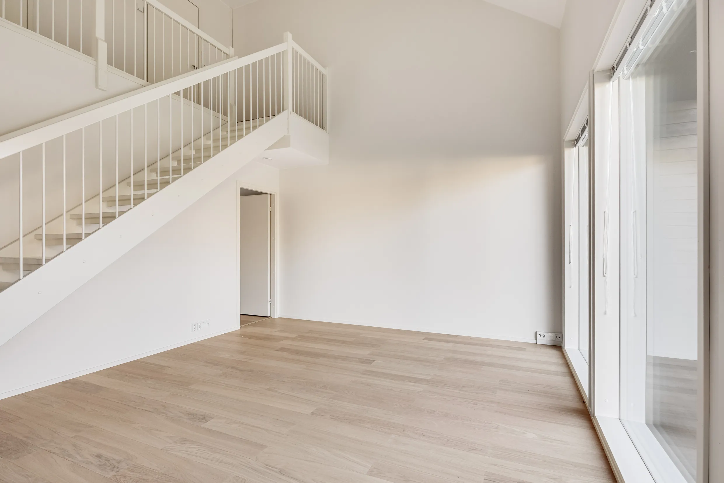 Vaalea huone, portaat, ikkunat.