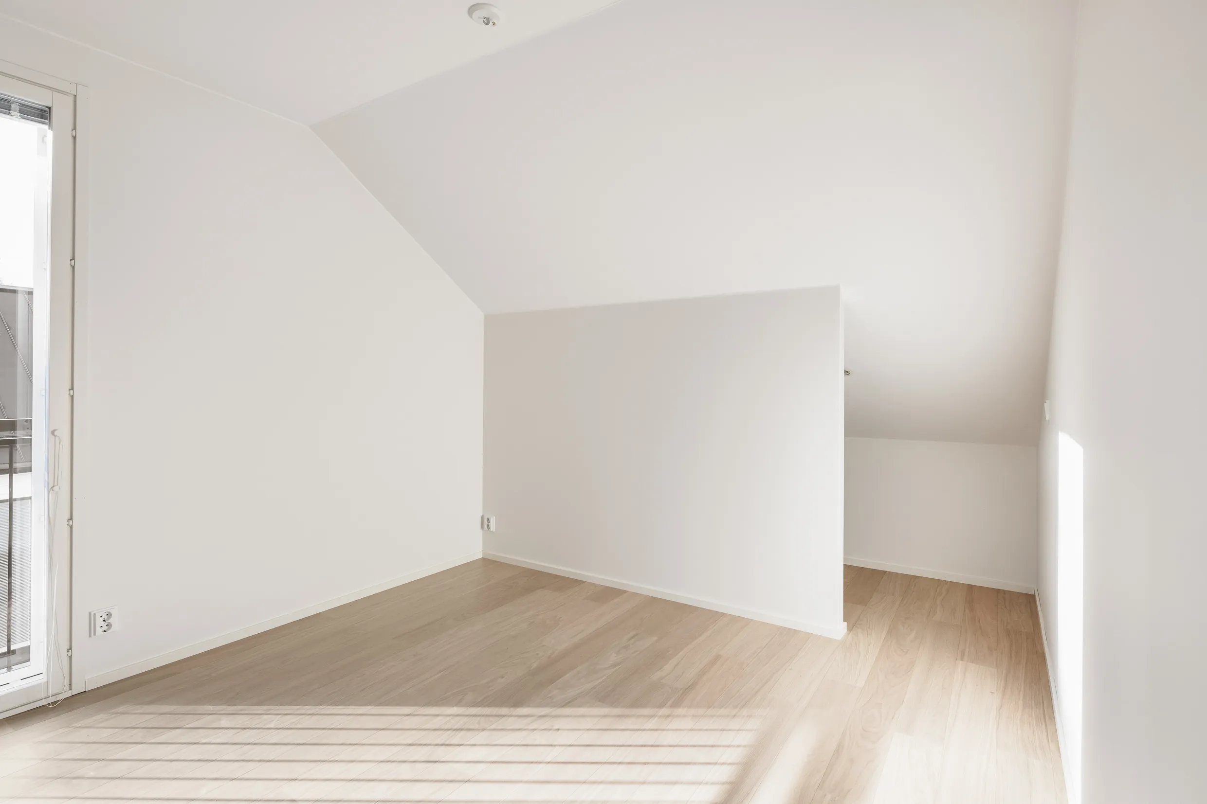 Vaalea huone, puulattia, valoisa.